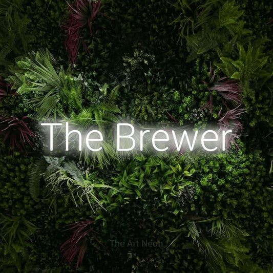 Cool white LED neon sign reading "The Brewer" against a lush garden wall with pink flowers