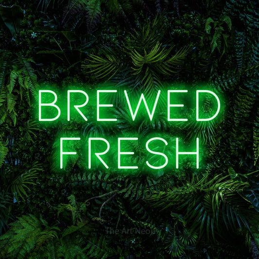 Green LED neon sign reading "Brewed Fresh" against a dense tropical foliage wall