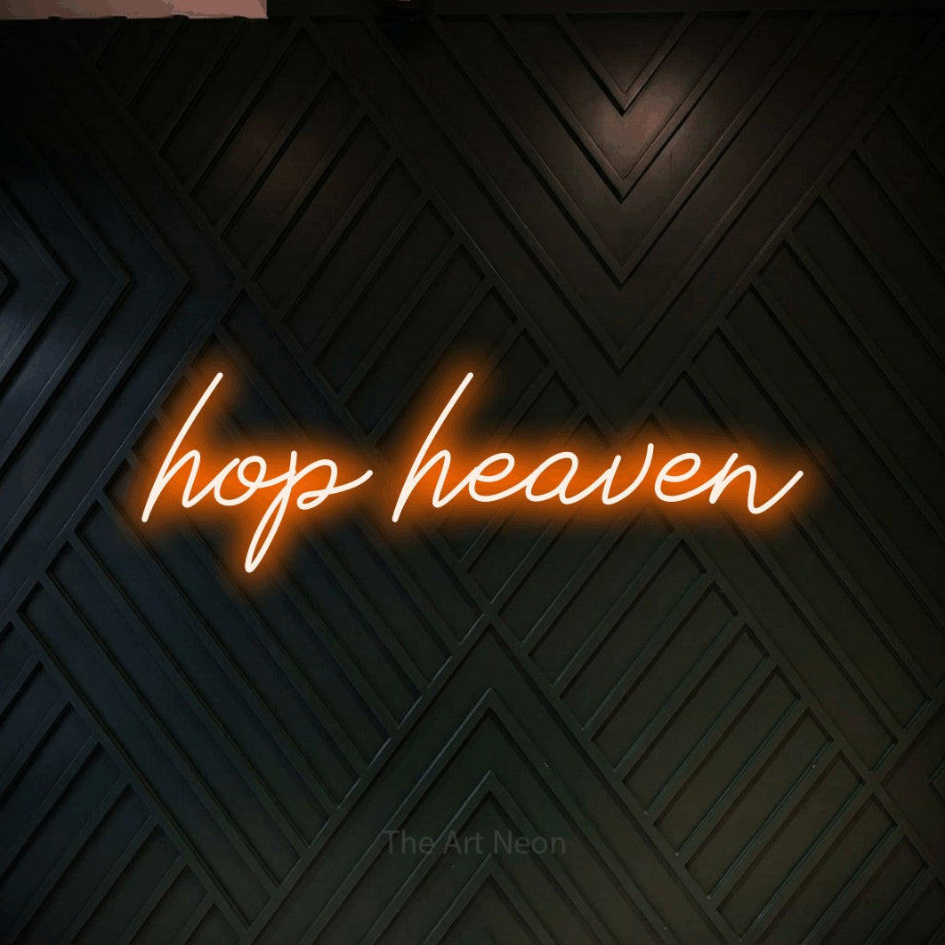 Enseigne néon à DEL à lumière orange, de style manuscrit, affichant « Hop Heaven » sur un mur géométrique en bois foncé