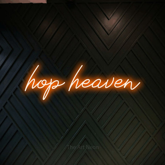 Orange script-style LED neon sign reading "Hop Heaven" against a dark geometric wood wall