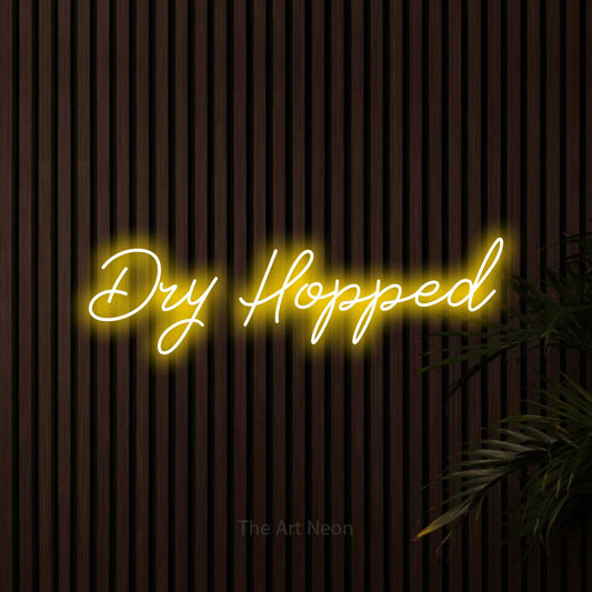 Yellow script-style LED neon sign reading "Dry Hopped" against dark wooden slats