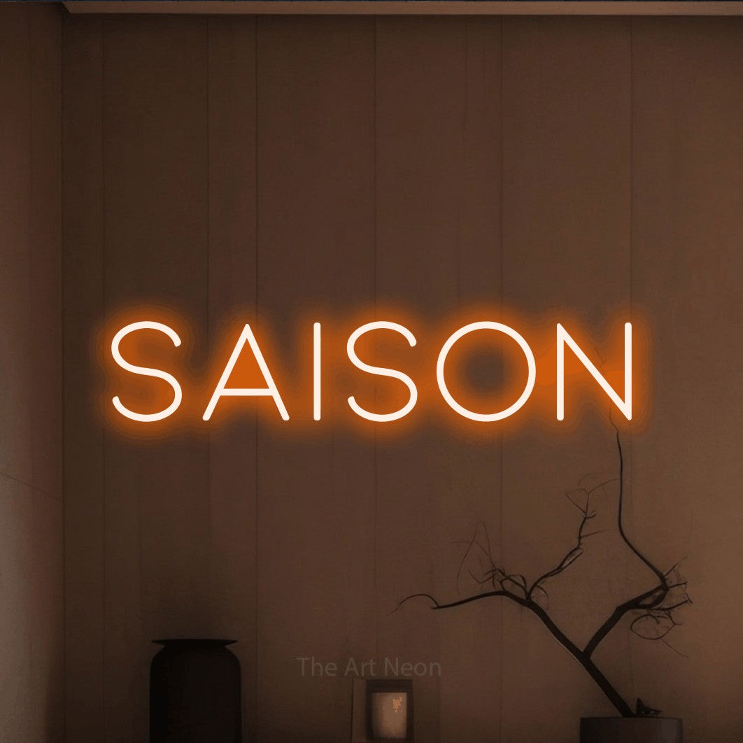 Orange LED neon sign reading "Saison" against a warm brown wall