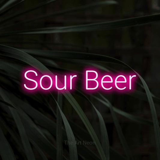 Hot pink LED neon sign reading "Sour Beer" against dark tropical leaves