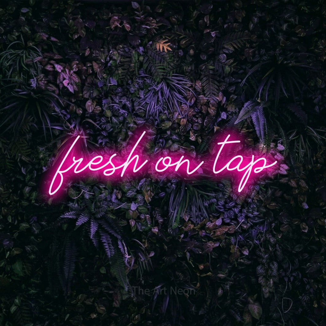 Hot pink script-style LED neon sign reading "Fresh on Tap" against a purple floral wall