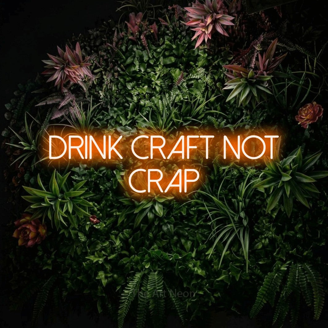 Orange LED neon sign reading "Drink Craft Not Crap" against a flowering garden wall