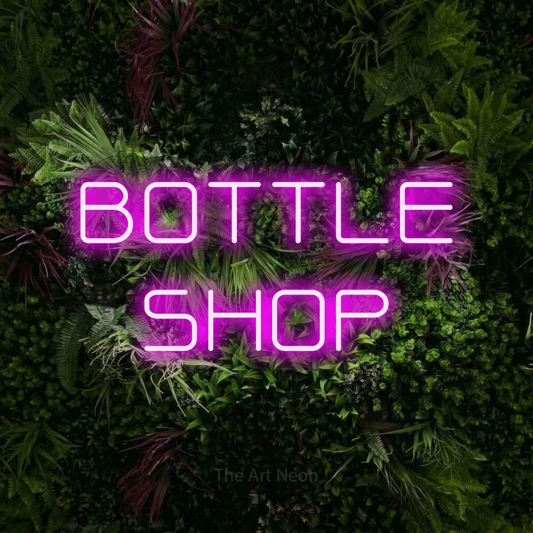 Pink LED neon sign reading "Bottle Shop" against a lush garden wall with pink flowers