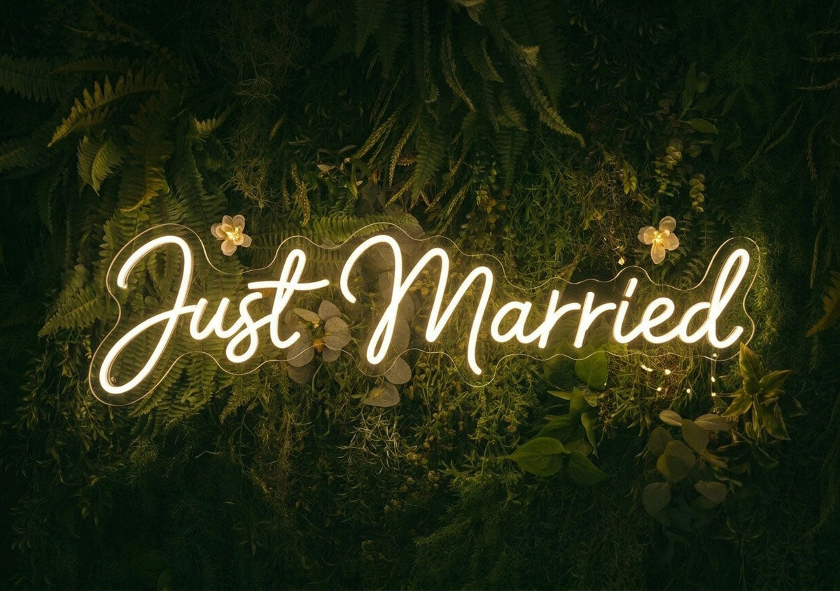Warm white Just Married LED neon sign displayed on a greenery wall