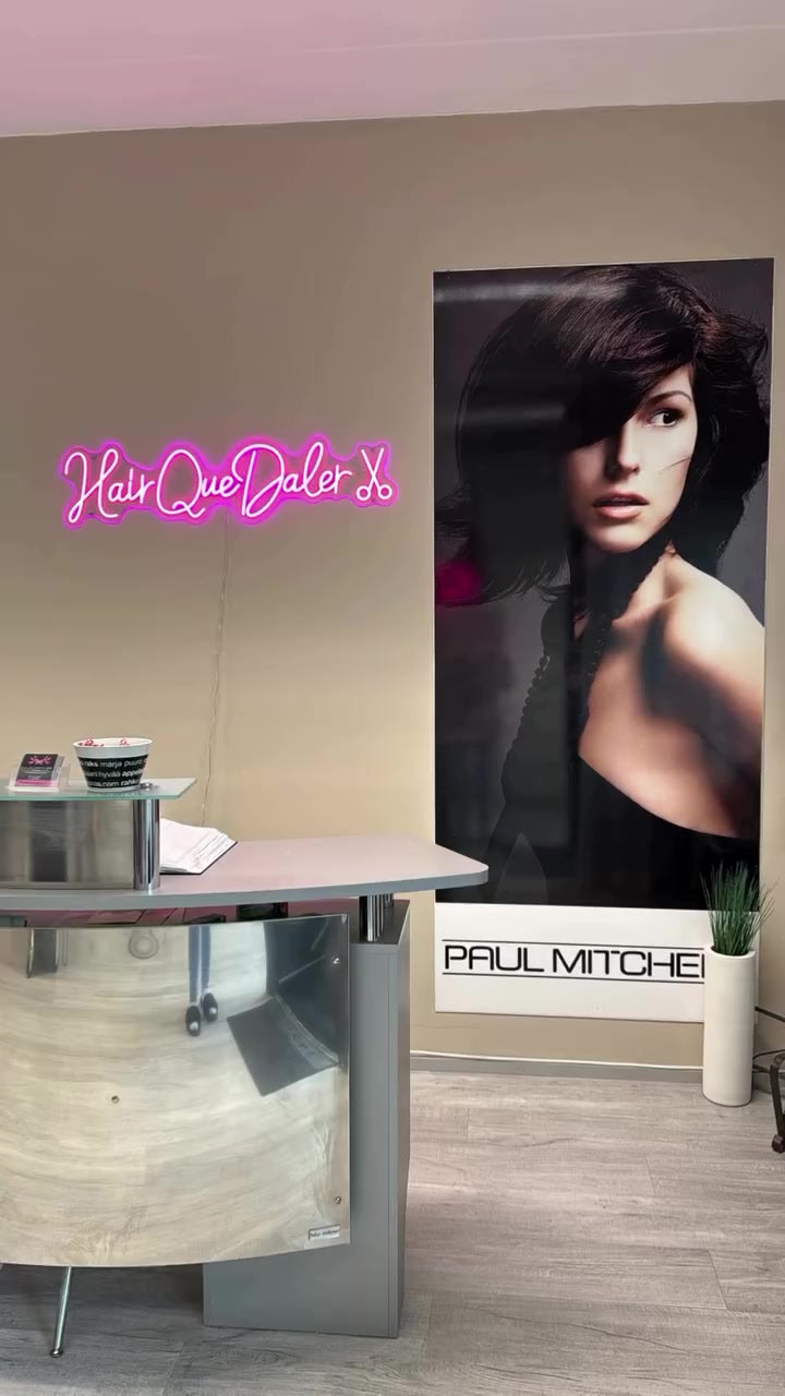 Pink Hair Que Daler signature-style LED neon installed above a salon reception desk.
