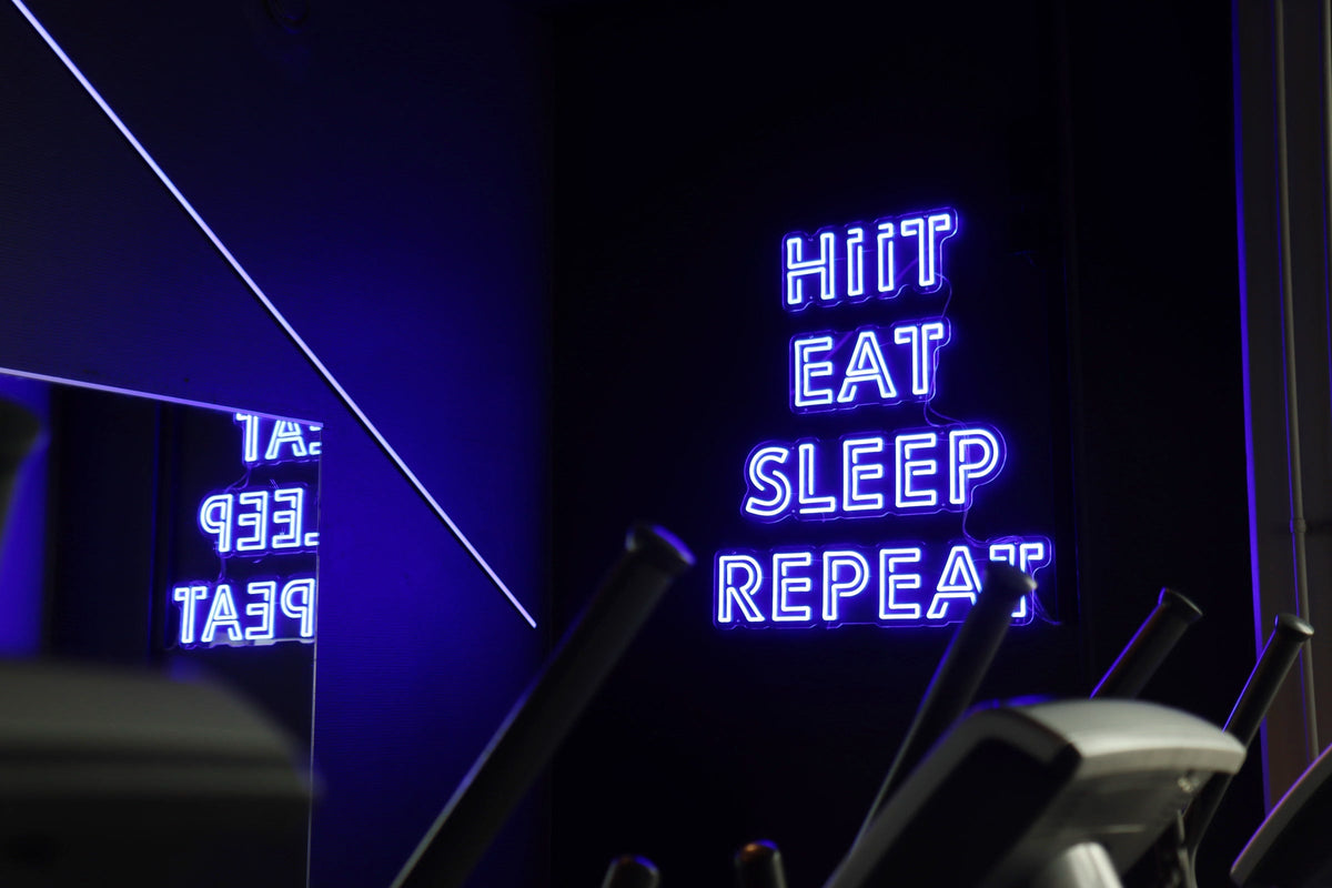 Blue HIIT EAT SLEEP REPEAT LED neon sign mounted inside Kuntomaailma gym in Jyväskylä.