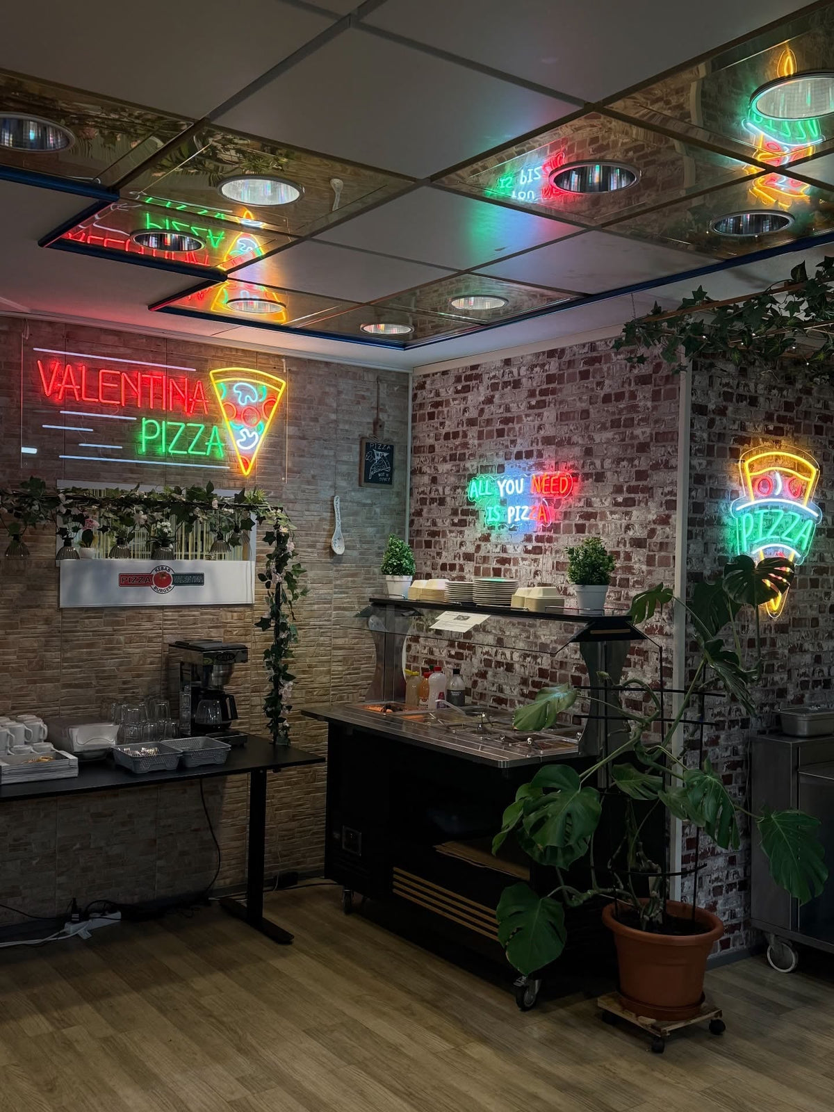 Multiple colourful Valentina Pizza LED neon signs installed across the restaurant’s brick feature walls.