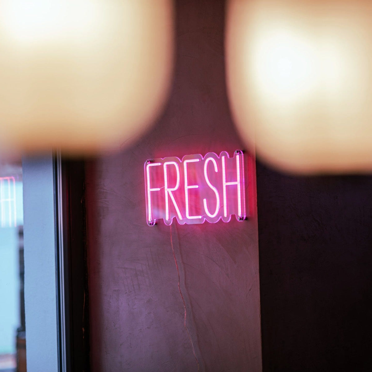 Pink vegan options LED neon sign on a wall inside Ichigo Budapest fusion restaurant.