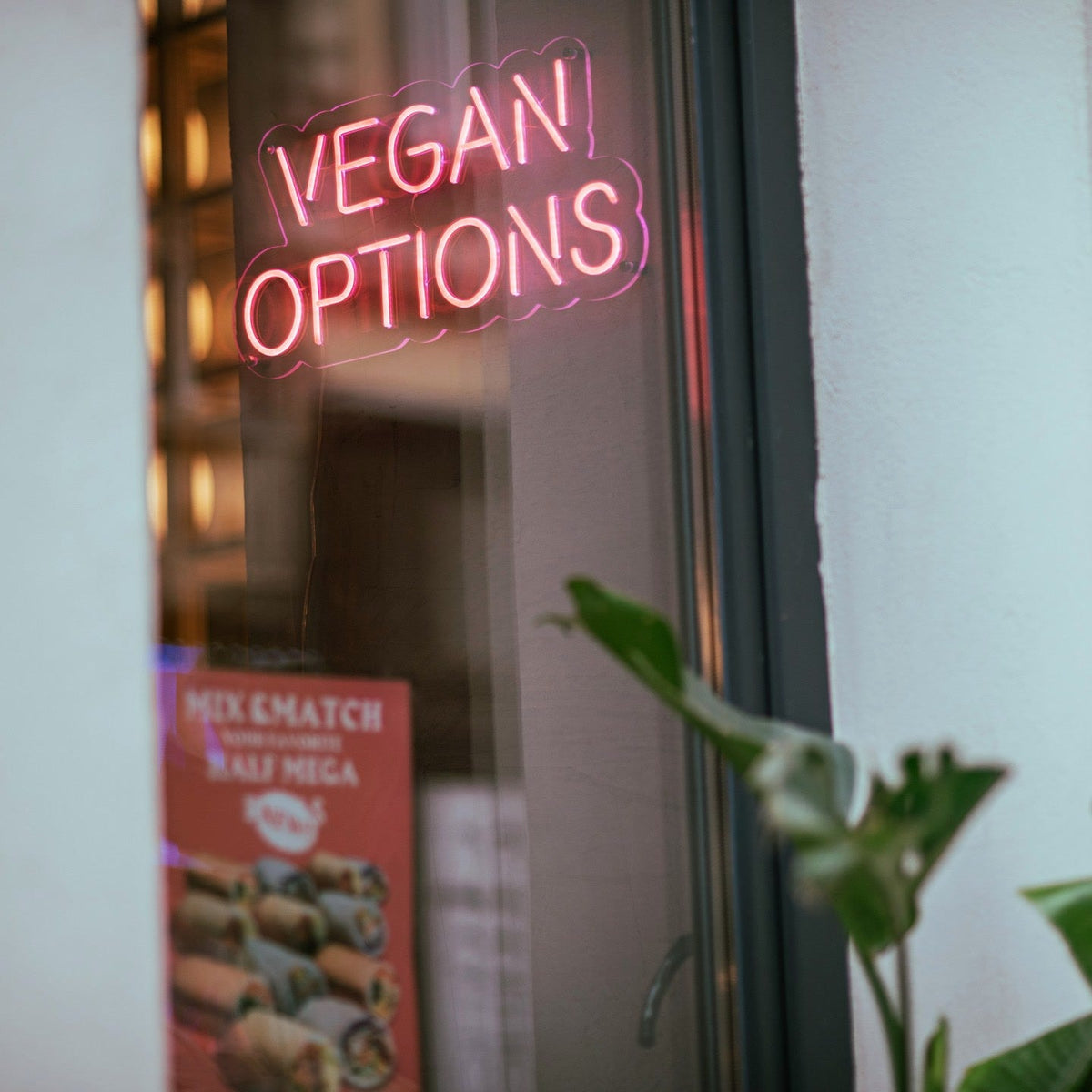 Pink vegan options LED neon sign on a wall inside Ichigo Budapest fusion restaurant.