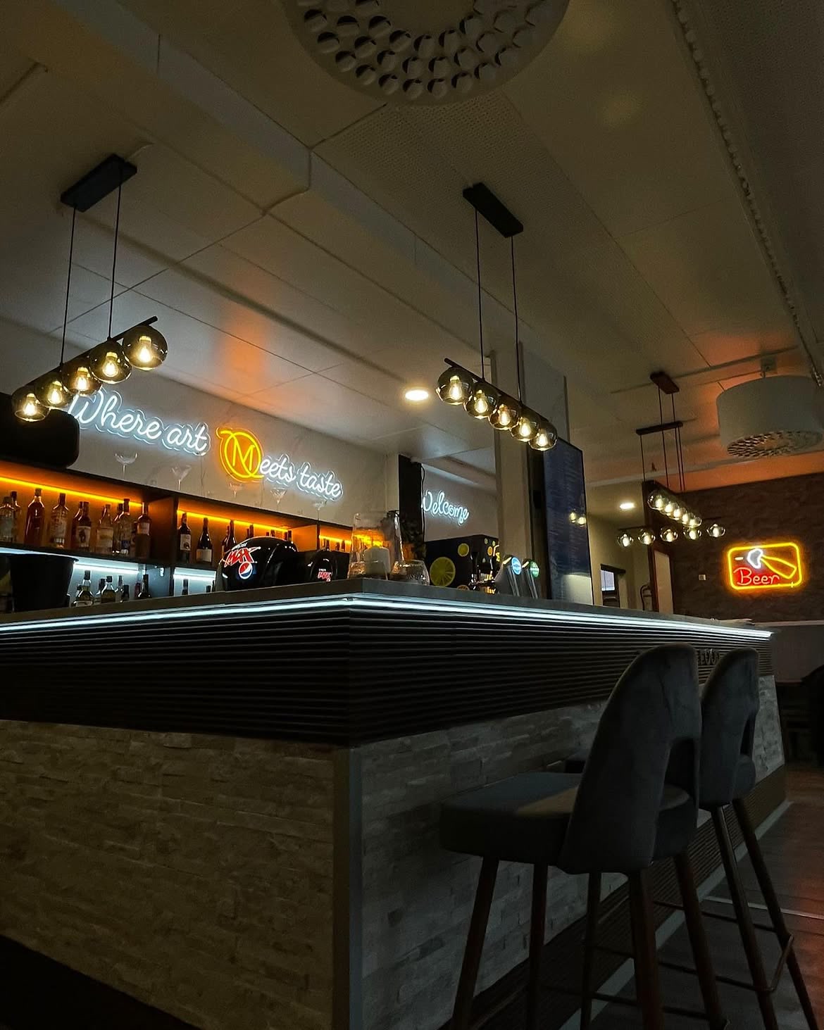 Warm-white WHERE ART MEETS TASTE LED neon installed above the Madez Lounge bar.