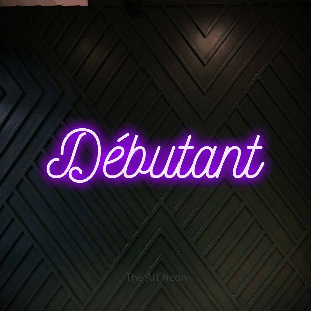 “Débutant” LED neon sign in purple, with ornate cursive lettering, shown against a black chevron-patterned wood wall.