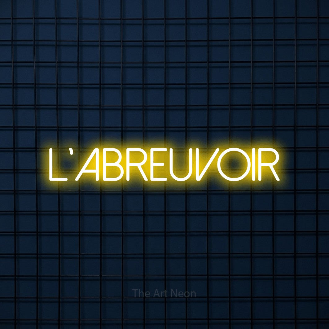 Aperçu d’une enseigne néon LED « L'abreuvoir » en jaune, en lettres fines sans empattement, photographiée sur une grille bleu foncé, pour un bar à la maison.
