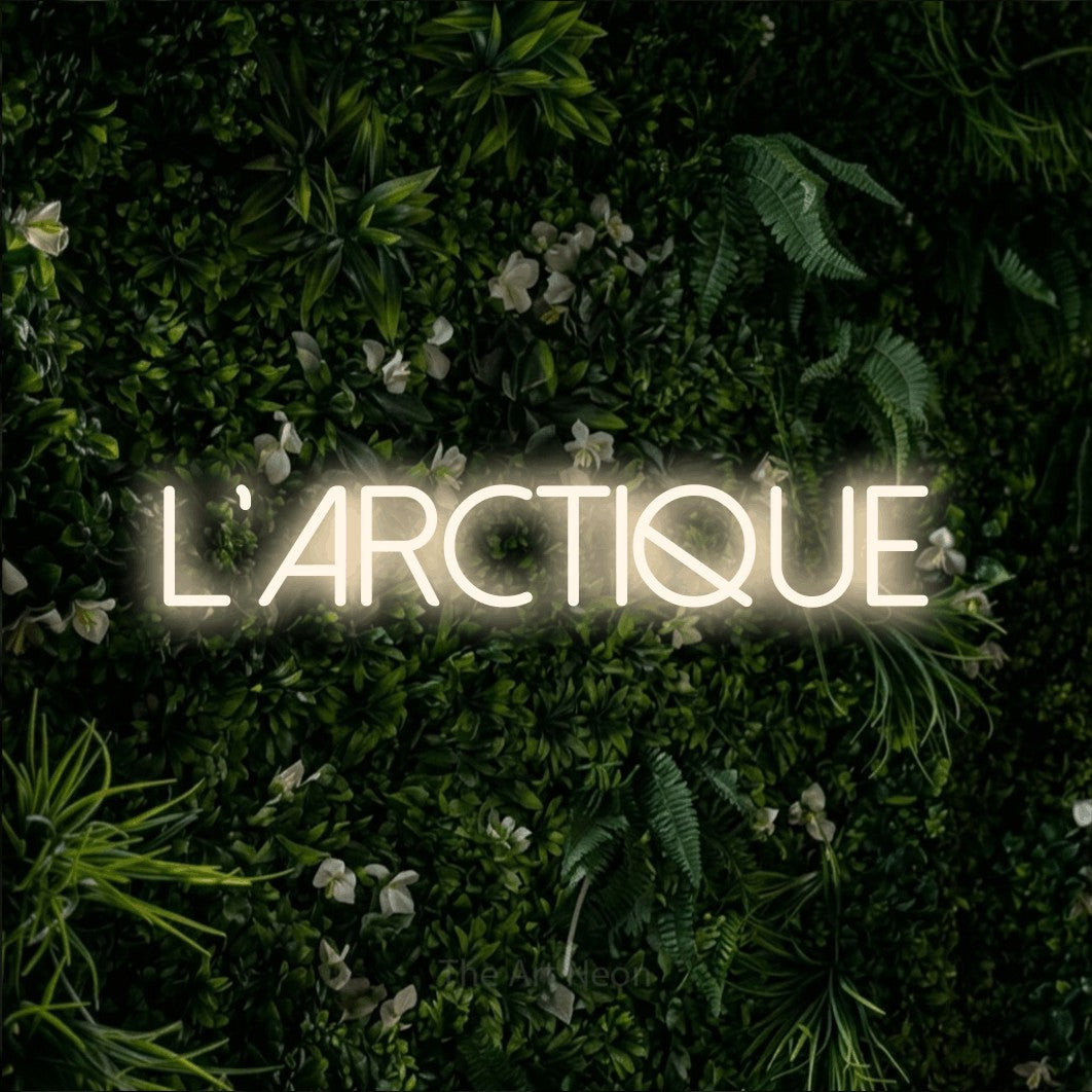Décoration murale en néon LED « L'arctique » en blanc chaud, en lettres fines sans empattement, installée sur un mur végétal vert et dense, pour un décor de plein air canadien.
