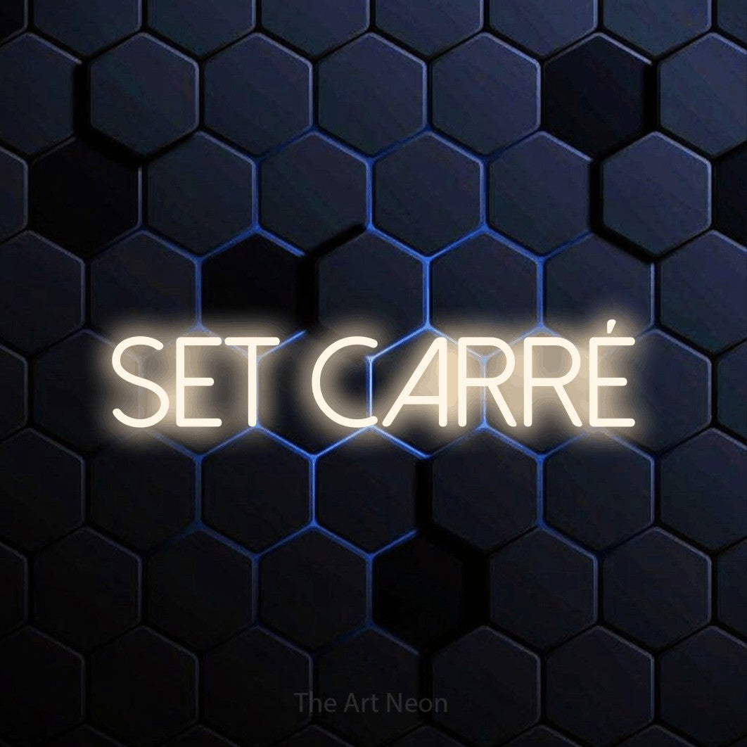 “Set carré” LED neon sign in warm white, with thin sans-serif lettering, shown against a dark blue honeycomb pattern.