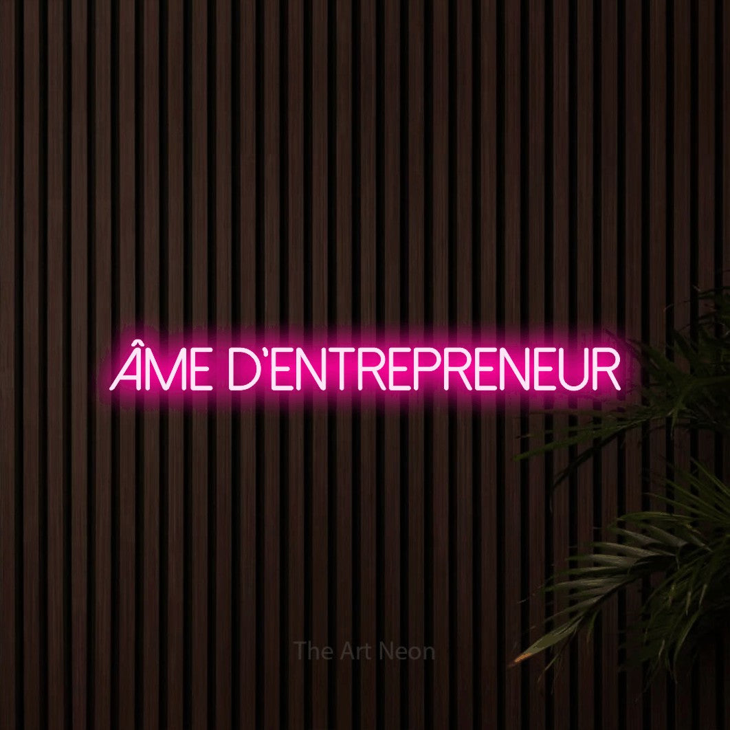 “Âme d'entrepreneur” LED neon sign in hot pink, with thin sans-serif lettering, shown against dark wooden wall slats.