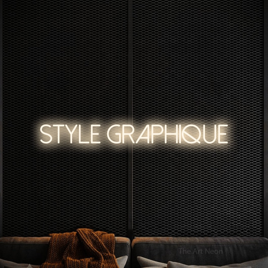 “Style graphique” LED neon sign in warm white, with thin sans-serif lettering, shown against a modern dark-toned seating area.