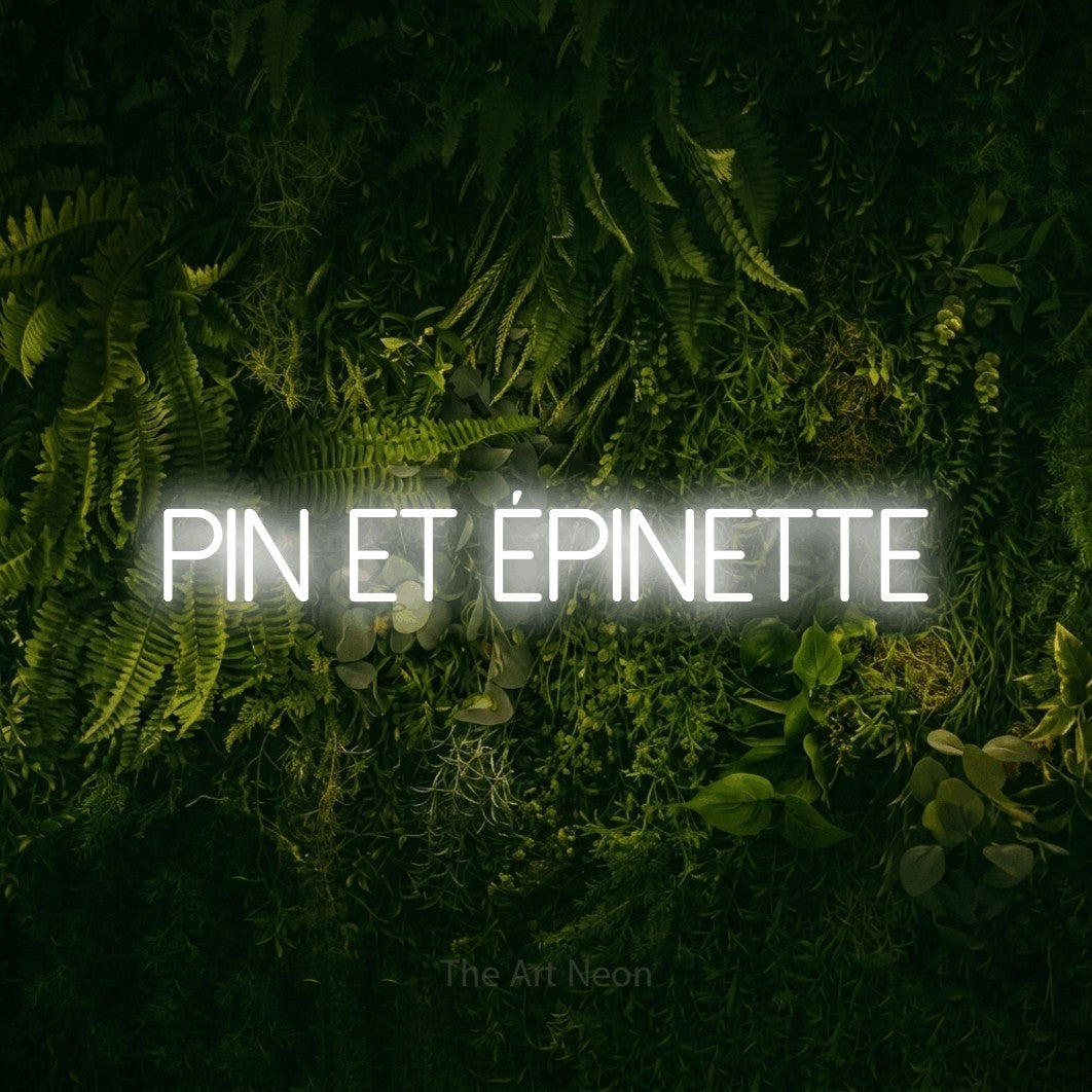 “Pin et épinette” LED neon sign in cool white, with thin sans-serif lettering, shown against a dark moss and forest backdrop.