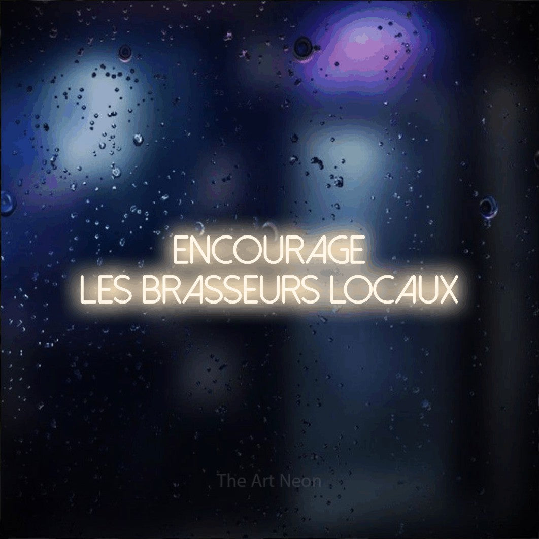 “Encourage les brasseurs locaux” LED neon sign in warm white, with thin sans-serif lettering across 2 lines, shown against glass with blue and purple reflections.