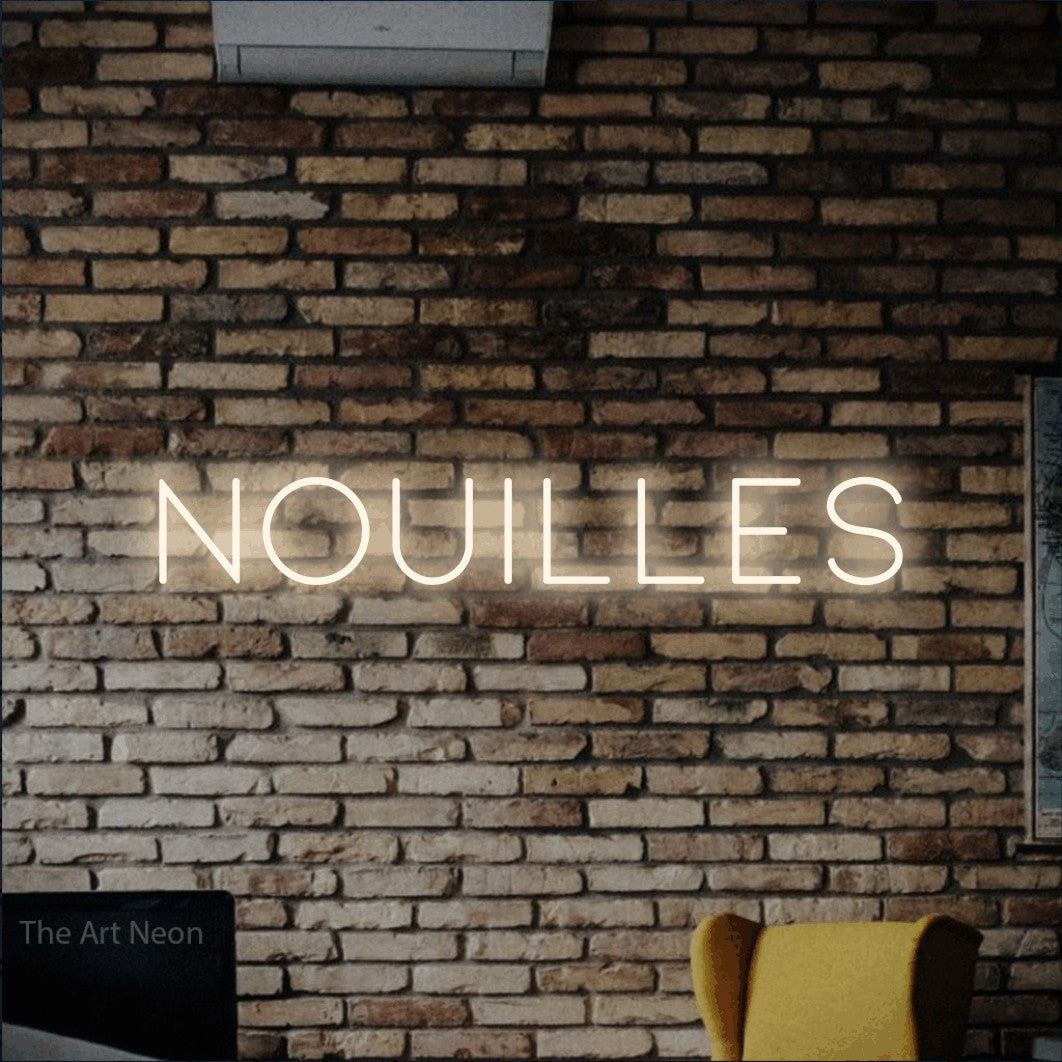 “Nouilles” LED neon sign in warm white, with thin, widely spaced lettering, shown against warm-toned brickwork.