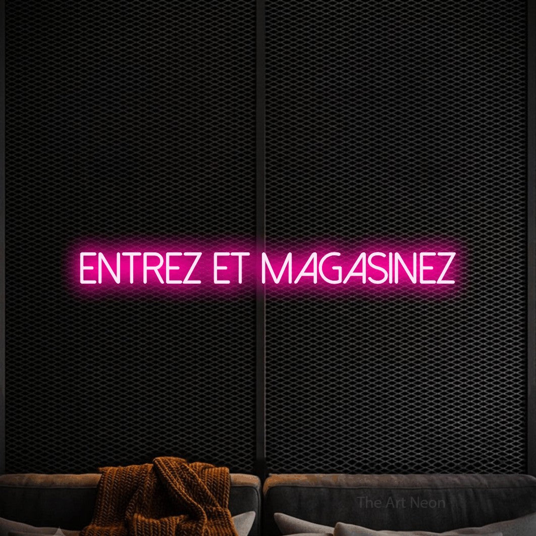 “Entrez et magasinez” LED neon sign in hot pink, with thin sans-serif lettering, shown against a modern dark-toned seating area.