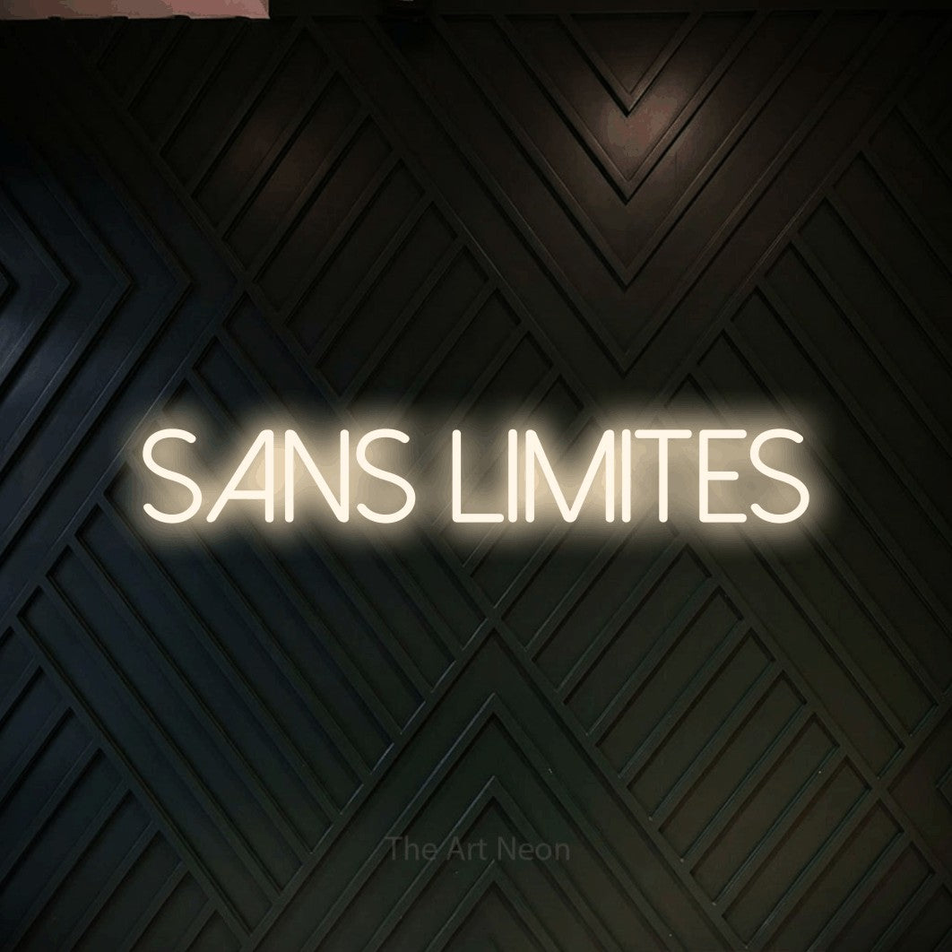 “Sans limites” LED neon sign in warm white, with thin sans-serif lettering, shown against a black chevron-patterned wood wall.