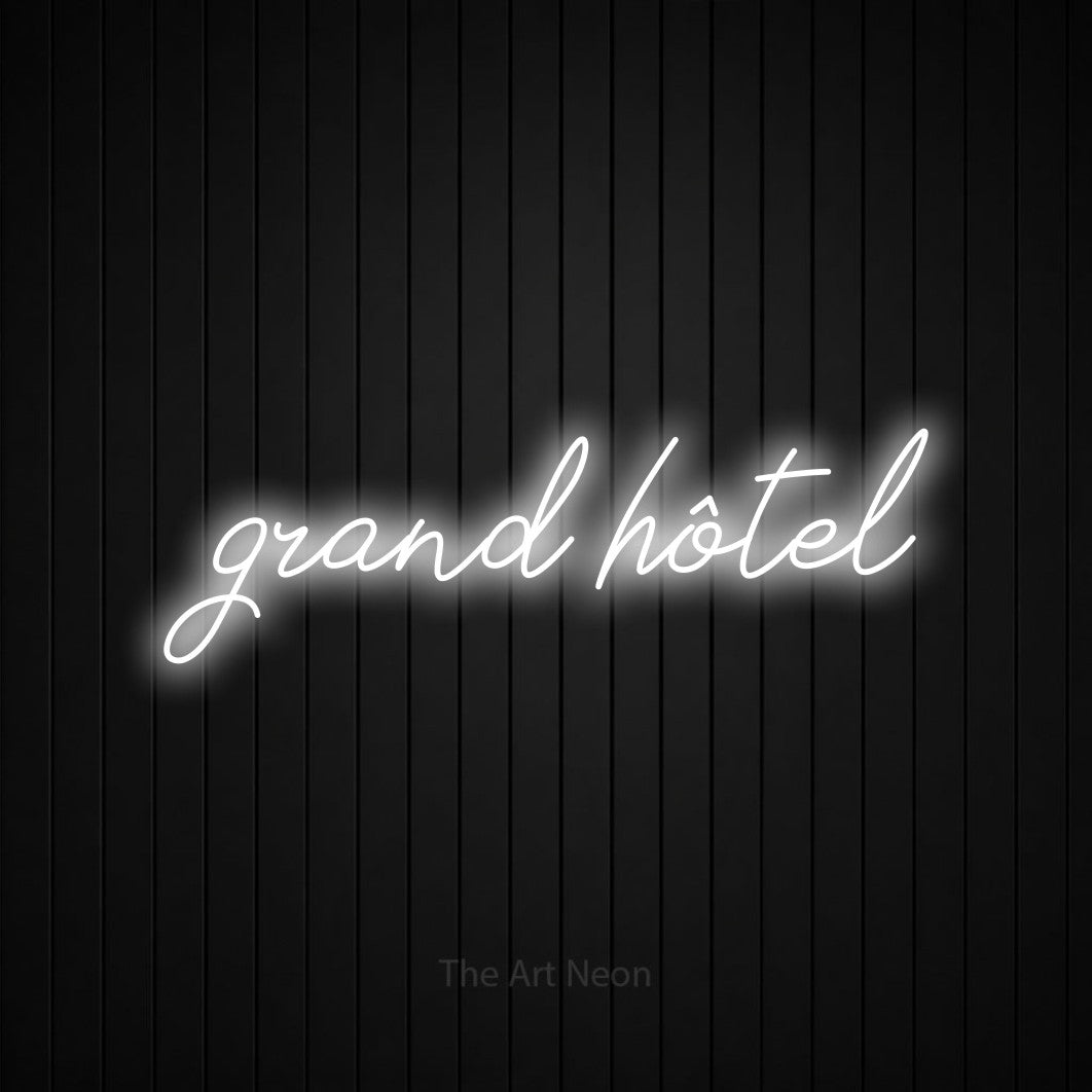 Lettrage en néon LED « Grand hôtel » en blanc froid, en lettrage cursif, présenté sur un mur de lattes verticales noires, pour un hôtel.