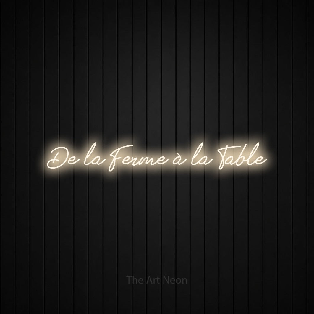 “De la ferme à la table” LED neon sign in warm white, with cursive lettering, shown against black vertical wall slats.