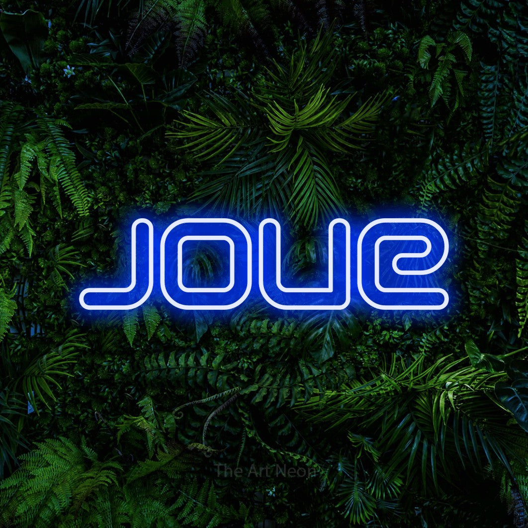 “Joue” LED neon sign in blue, with futuristic double-line lettering, shown against dense tropical foliage.