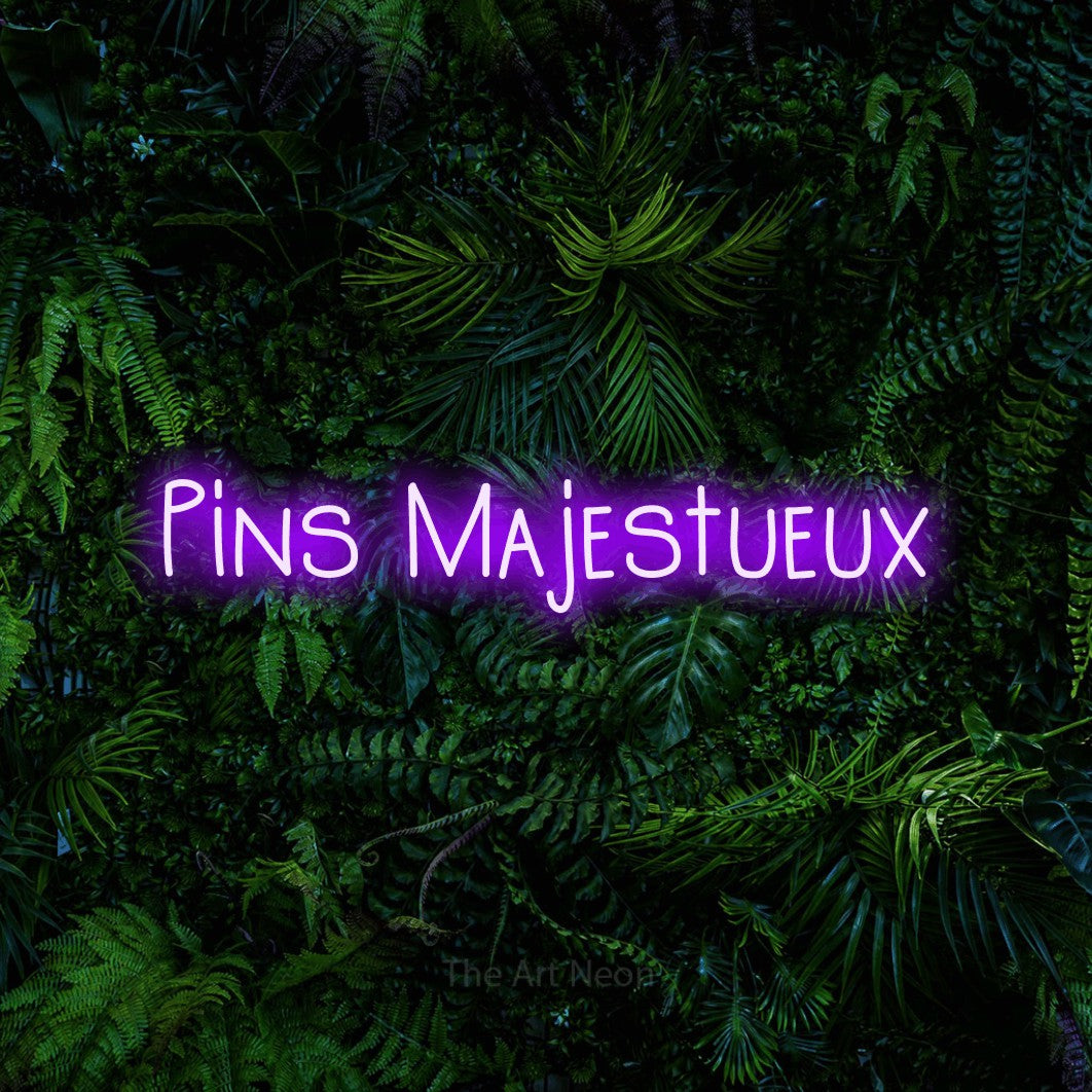 “Pins majestueux” LED neon sign in purple, with narrow hand-drawn lettering, shown against dense tropical foliage.