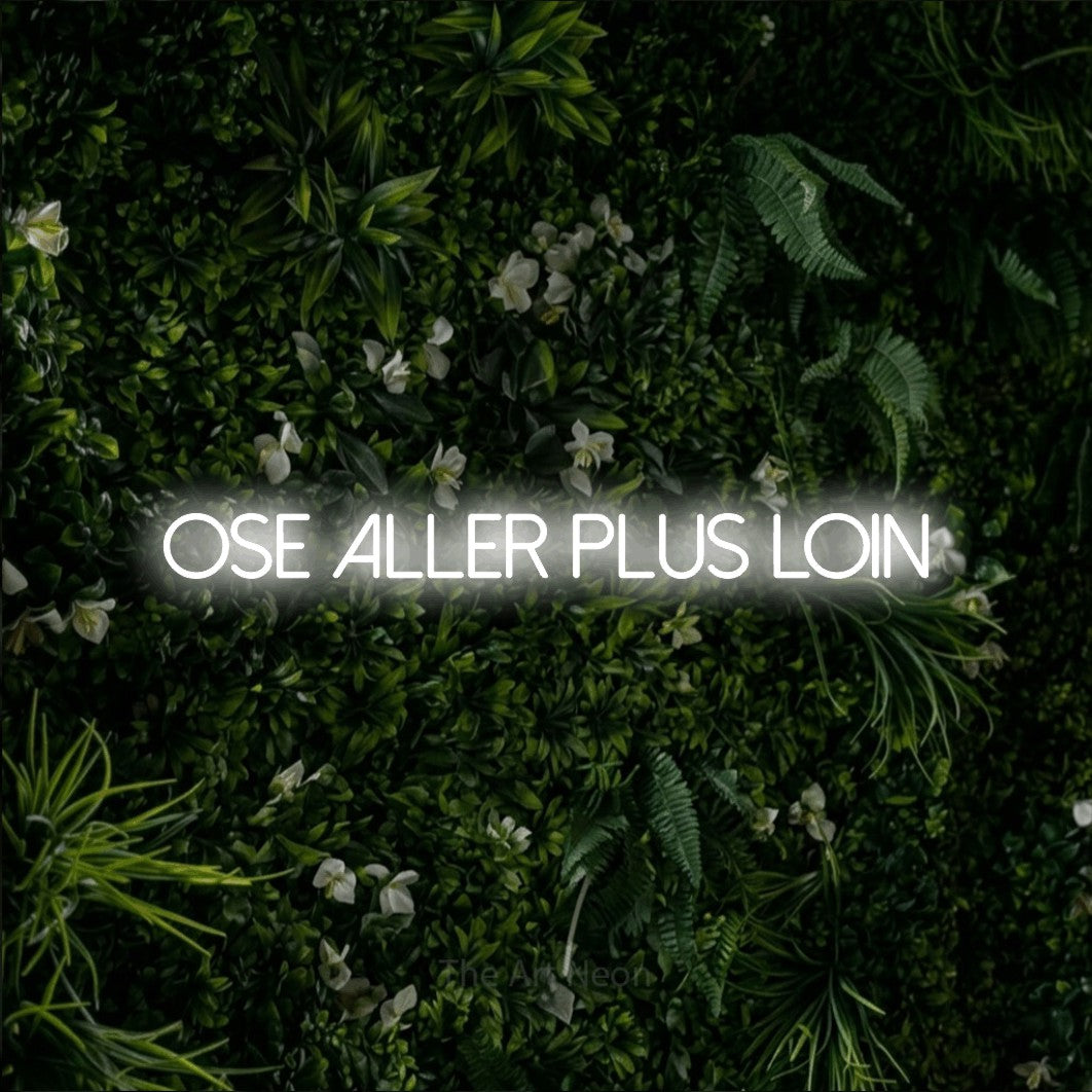 “Ose aller plus loin” LED neon sign in cool white, with thin sans-serif lettering, shown against a dense green plant wall.