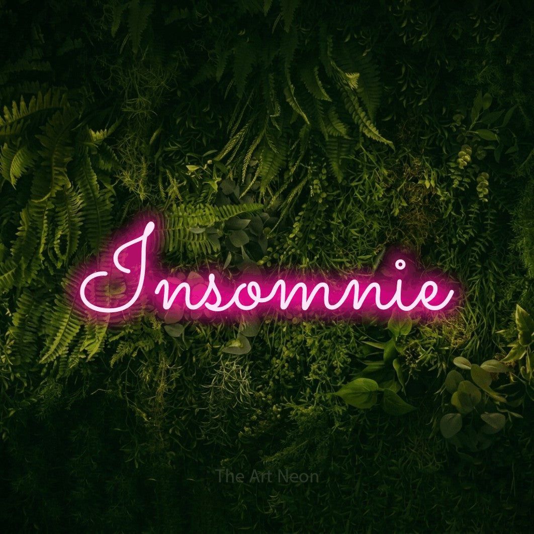 “Insomnie” LED neon sign in hot pink, with looped cursive lettering, shown against a dark moss and forest backdrop.