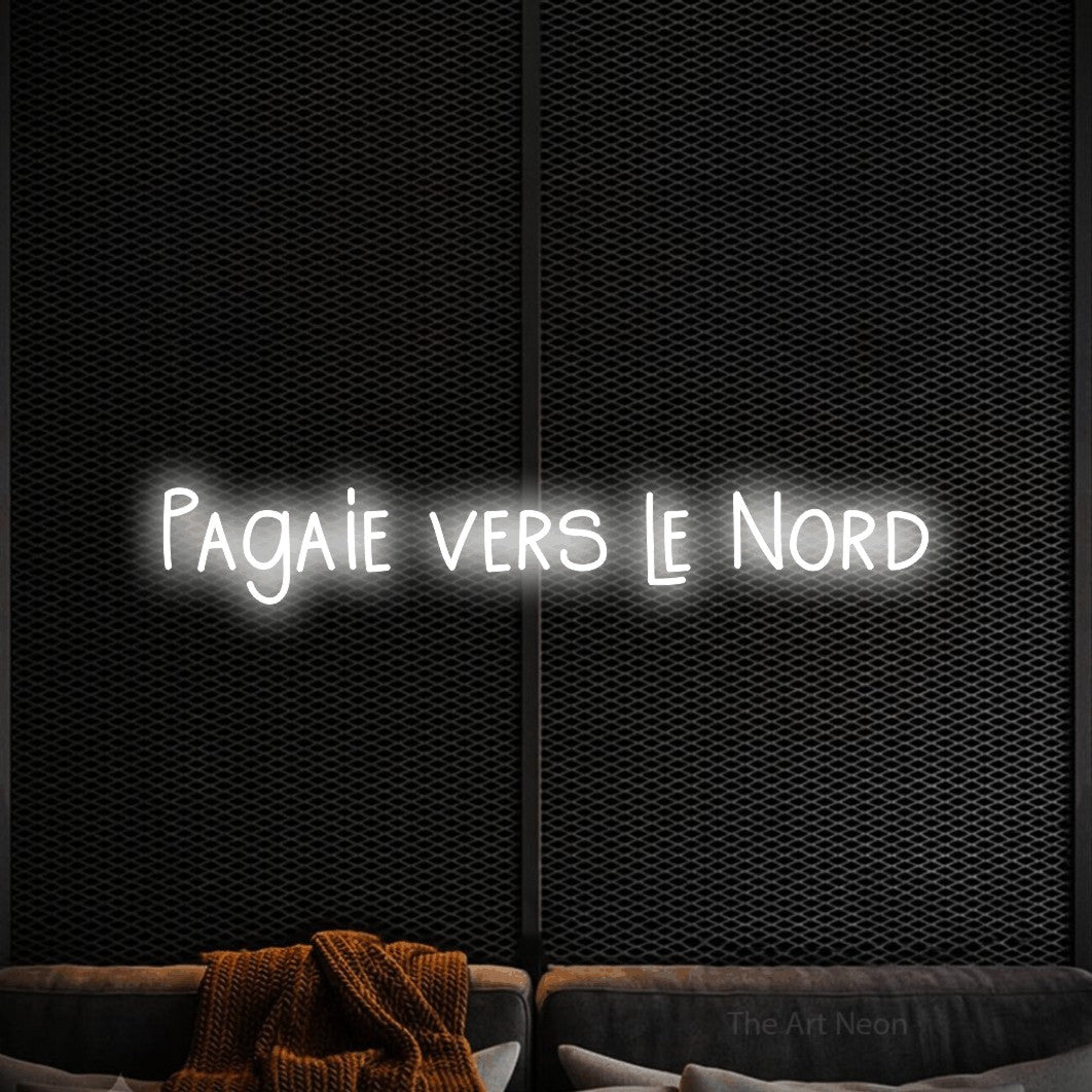 “Pagaie vers le nord” LED neon sign in cool white, with narrow hand-drawn lettering, shown against a modern dark-toned seating area.