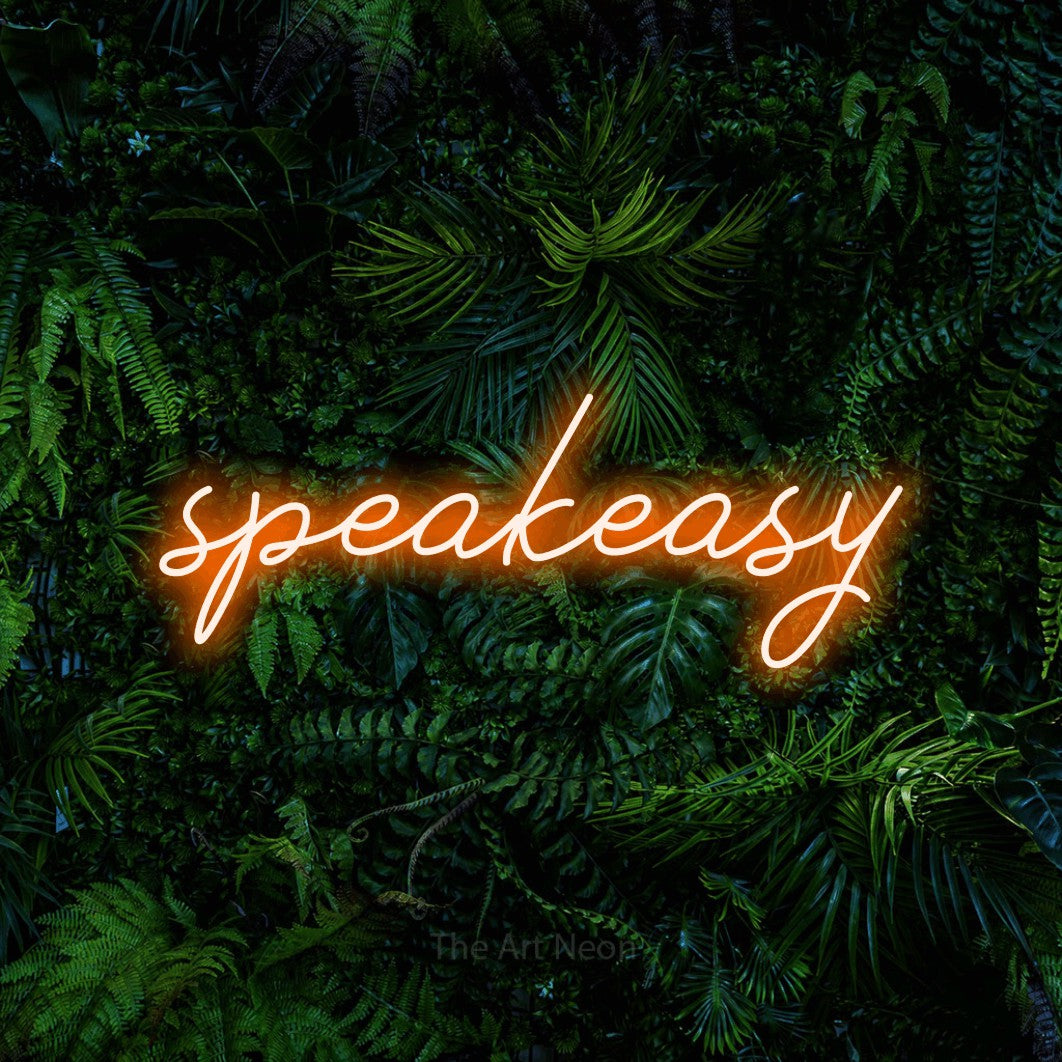 Aperçu d’une enseigne néon LED « Speakeasy » en orange, en lettrage cursif, photographiée devant un feuillage tropical dense, pour un bar à la maison.