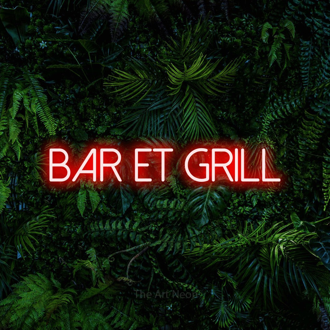“Bar et grill” LED neon sign in red, with thin sans-serif lettering, shown against dense tropical foliage.