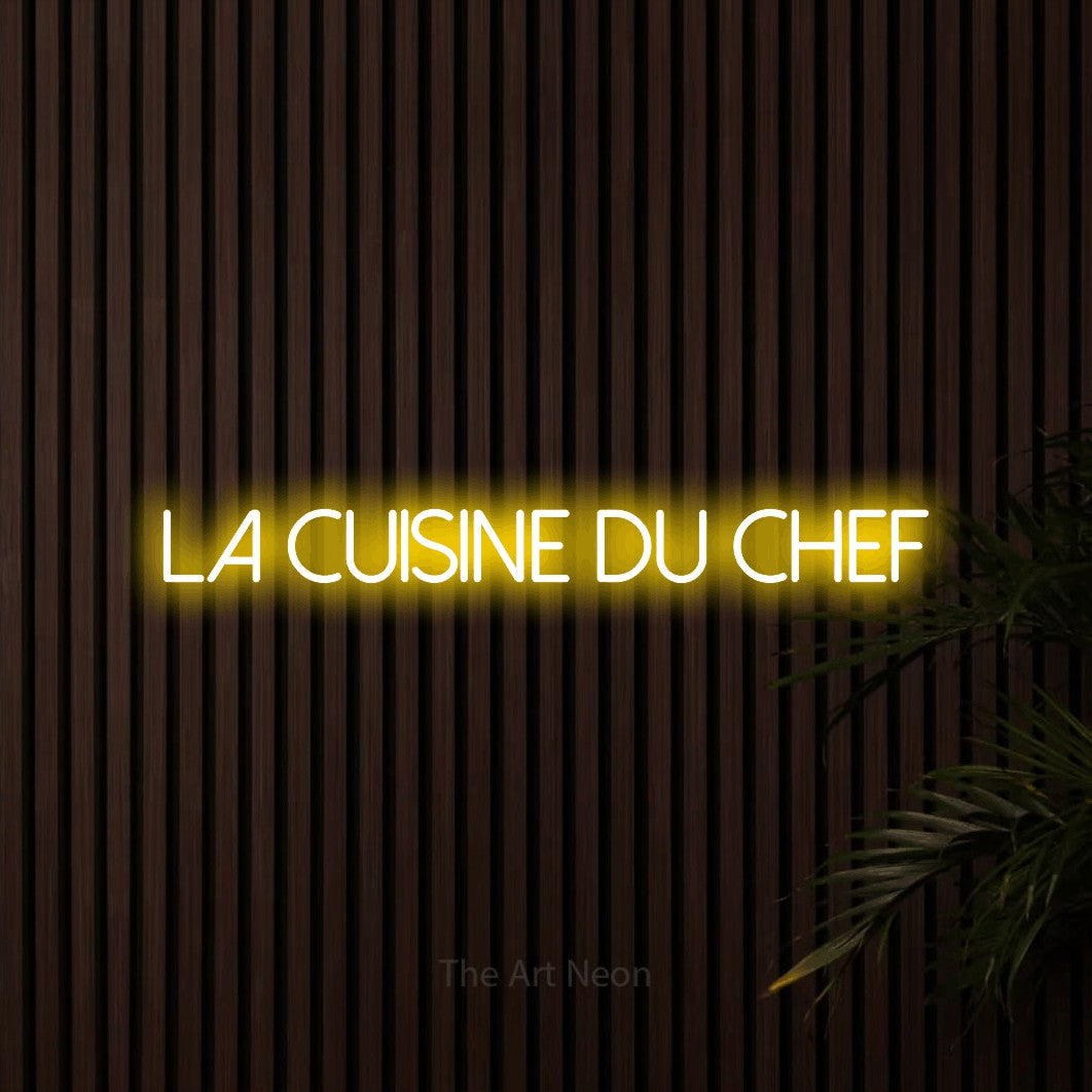 “La cuisine du chef” LED neon sign in yellow, with thin sans-serif lettering, shown against dark wooden wall slats.