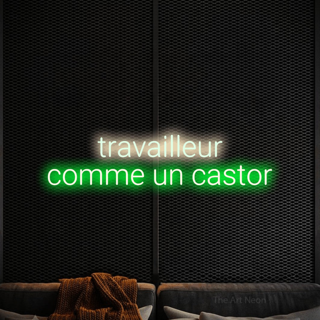 Néon LED « Travailleur comme un castor » sur deux lignes, blanc chaud en haut et vert en bas, en lettres sans empattement arrondies, mis en scène dans un coin salon moderne aux tons noirs, pour un décor canadien.