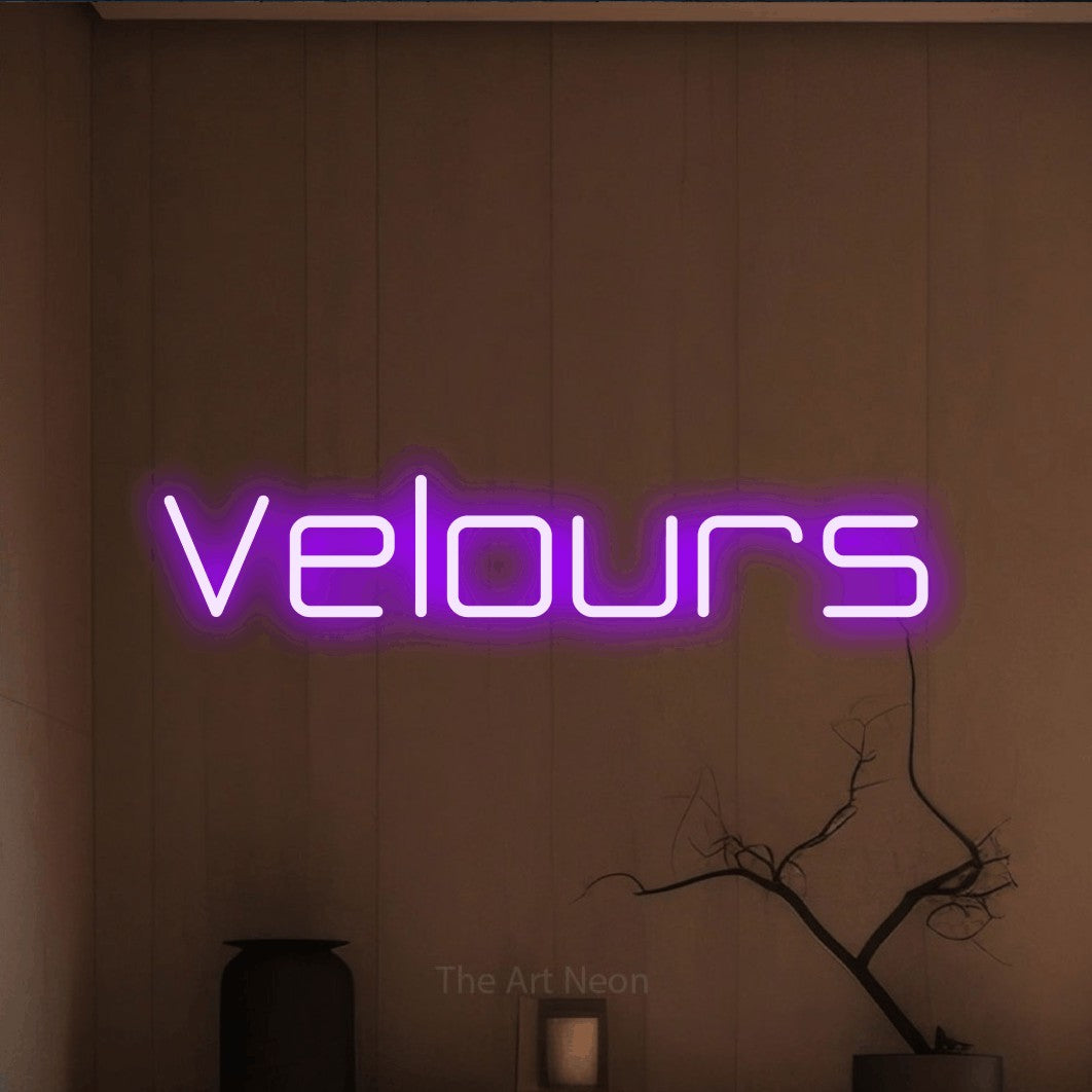 “Velours” LED neon sign in purple, with rounded geometric lettering, shown against a simple earth-toned interior.
