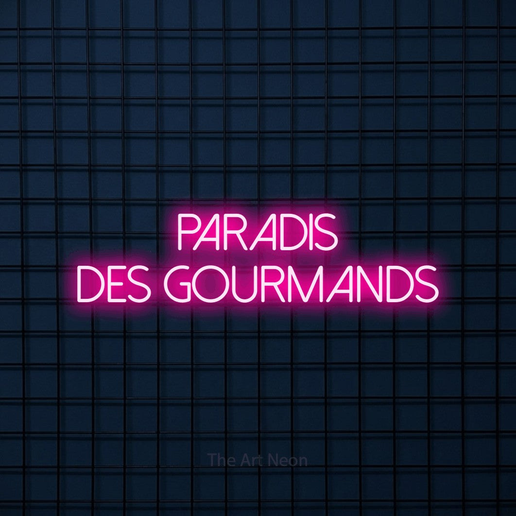“Paradis des gourmands” LED neon sign in hot pink, with thin sans-serif lettering across 2 lines, shown against a dark blue grid.