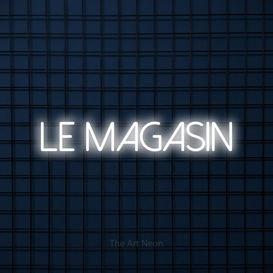 “Le magasin” LED neon sign in cool white, with thin sans-serif lettering, shown against a dark blue grid.