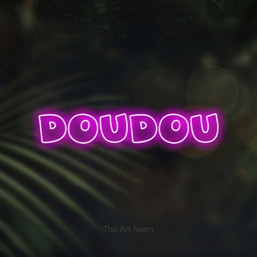 “Doudou” LED neon sign in pink, with wide lettering with irregular outlines, shown against a blurred palm and bokeh-light backdrop.