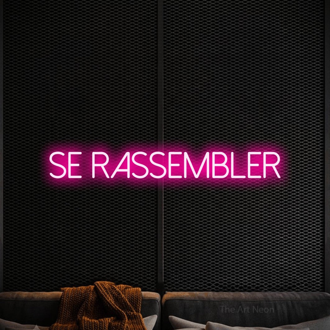 “Se rassembler” LED neon sign in hot pink, with thin sans-serif lettering, shown against a modern dark-toned seating area.