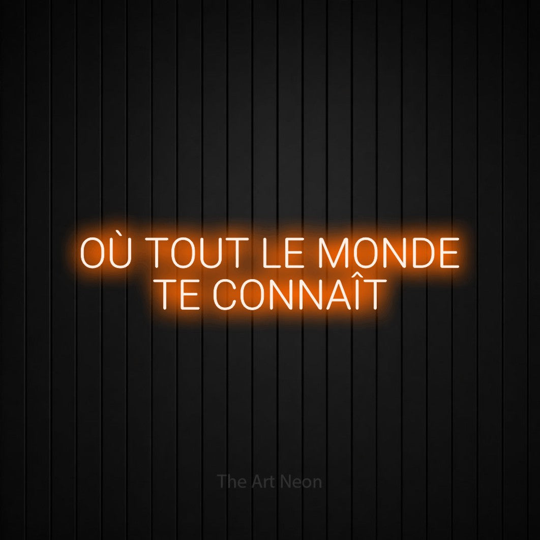 “Où tout le monde te connaît” LED neon sign in orange, with rounded sans-serif lettering across 2 lines, shown against black vertical wall slats.