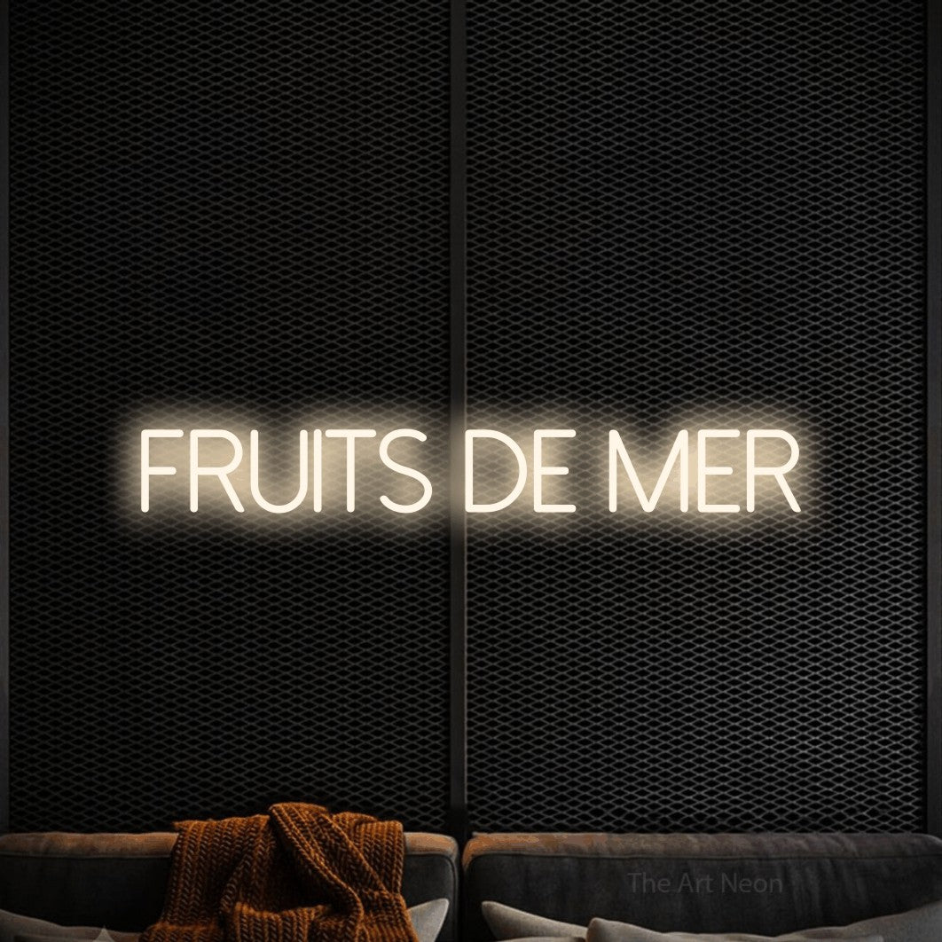 “Fruits de mer” LED neon sign in warm white, with thin sans-serif lettering, shown against a modern dark-toned seating area.