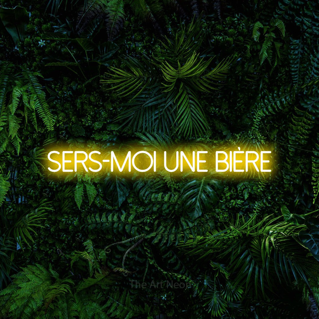 “Sers-moi une bière” LED neon sign in yellow, with thin sans-serif lettering, shown against dense tropical foliage.