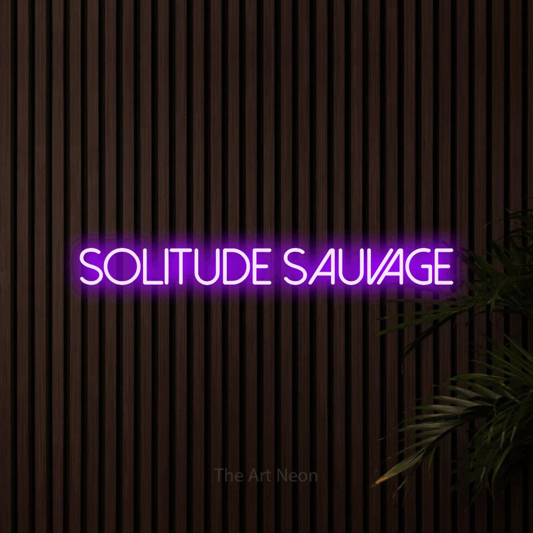 “Solitude sauvage” LED neon sign in purple, with thin sans-serif lettering, shown against dark wooden wall slats.