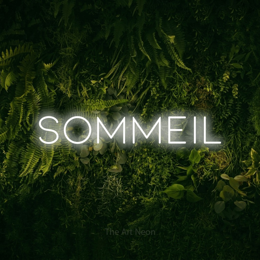 “Sommeil” LED neon sign in cool white, with thin, widely spaced lettering, shown against a dark moss and forest backdrop.