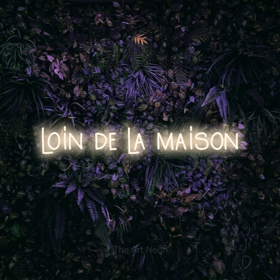 Néon LED « Loin de la maison » en blanc chaud, en lettres étroites dessinées à la main, mis en scène sur un mur sombre aux fleurs violettes, pour un hôtel.